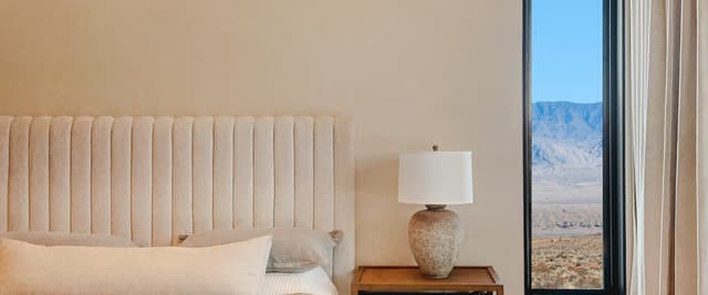 Warm desert-toned vacation rental bedroom with Southwest mountain view through the window